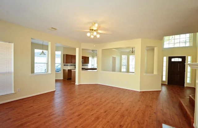 a view of an empty room with window and wooden floor