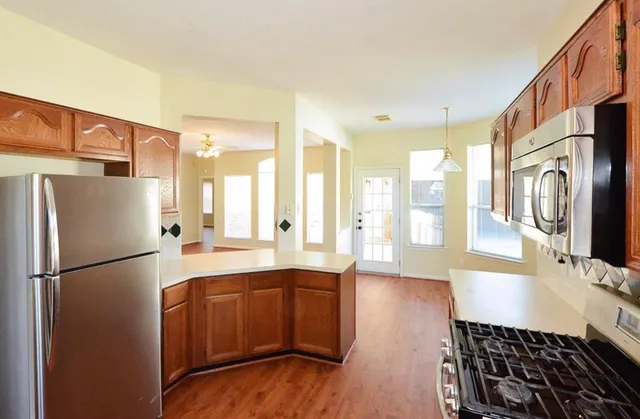 a kitchen with stainless steel appliances granite countertop a refrigerator a stove a sink and a microwave