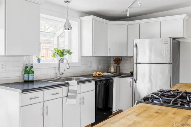 a kitchen with stainless steel appliances granite countertop a refrigerator a sink a counter space and cabinets