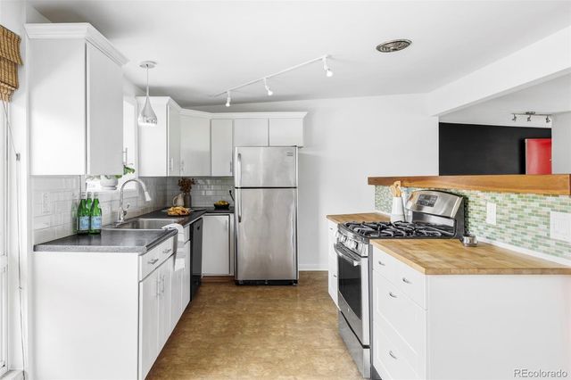 a kitchen with stainless steel appliances granite countertop a stove top oven a sink a refrigerator and a refrigerator