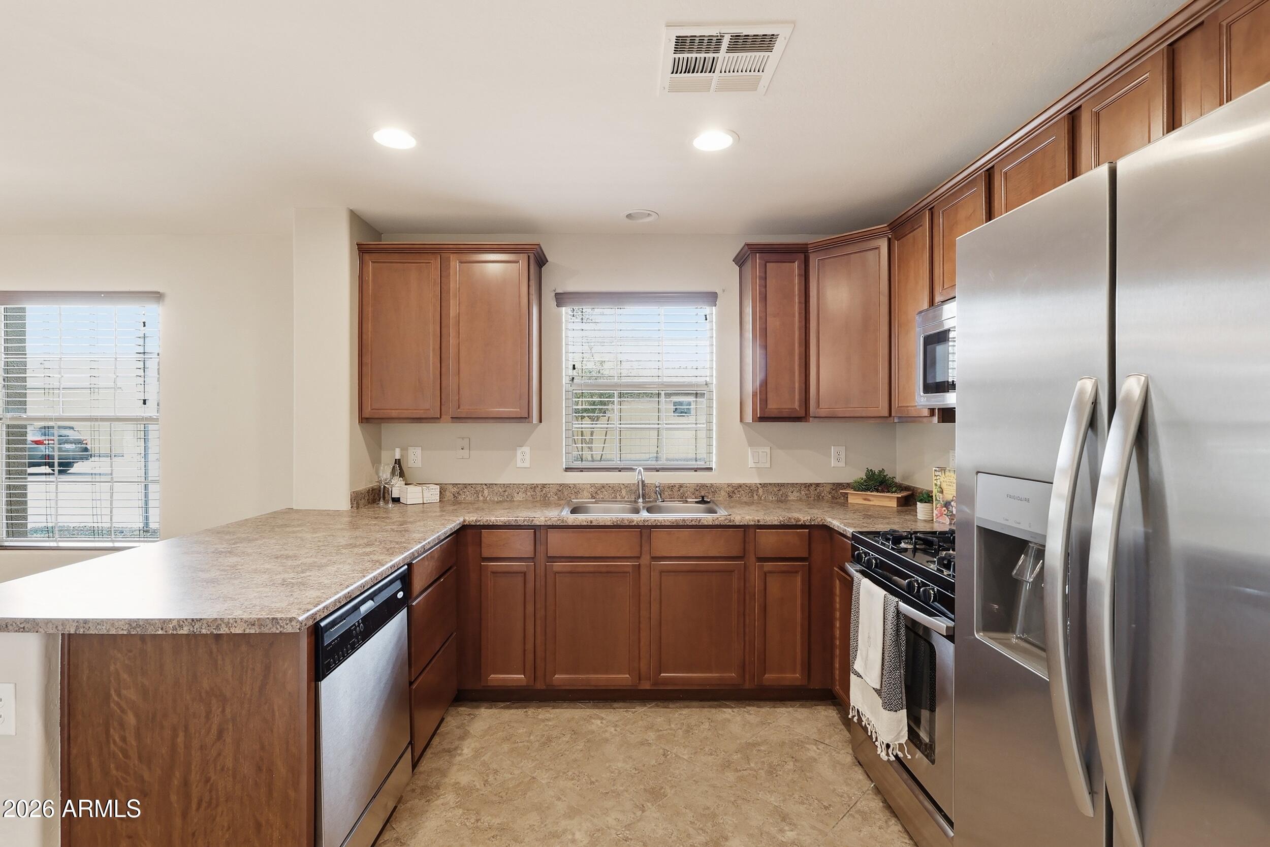 1853 South Balboa Drive Gilbert, AZ 85295 - Photo 12 of 32 a kitchen with stainless steel appliances granite countertop a sink stove and refrigerator