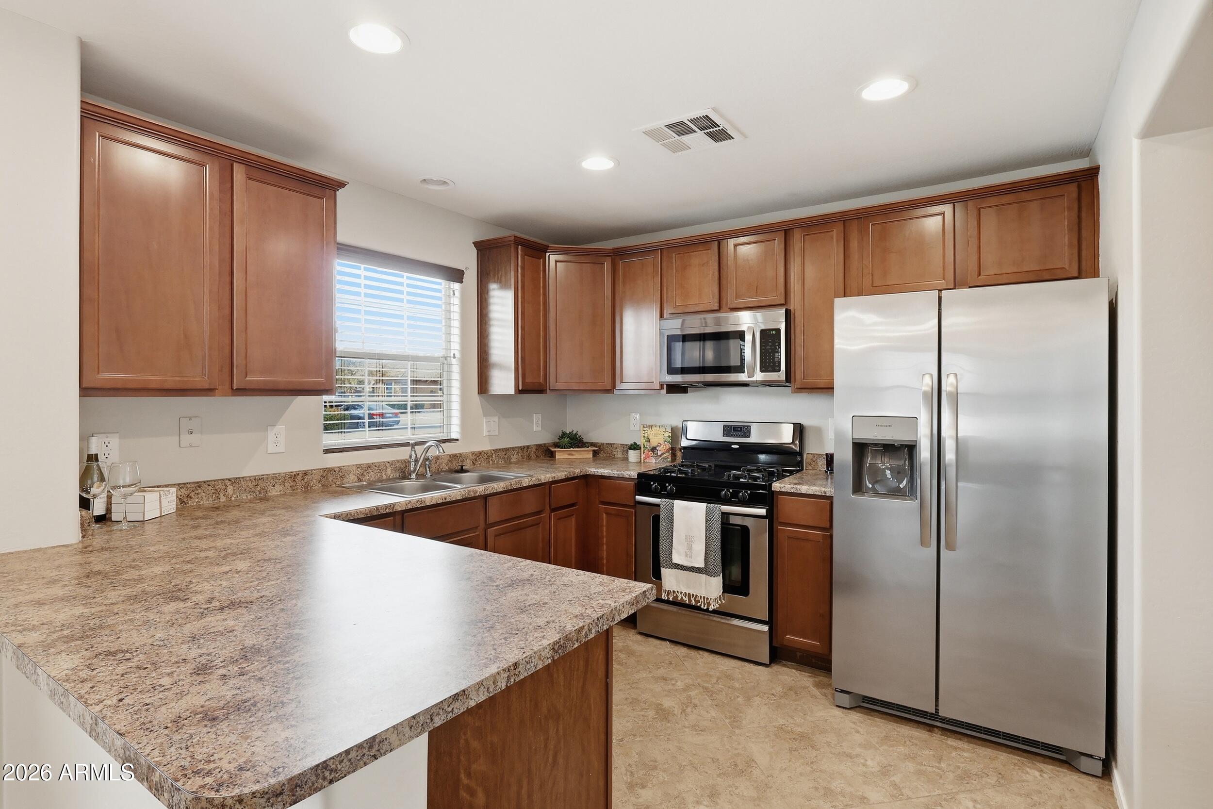 1853 South Balboa Drive Gilbert, AZ 85295 - Photo 13 of 32 a kitchen with stainless steel appliances granite countertop a refrigerator a sink a stove a microwave and island