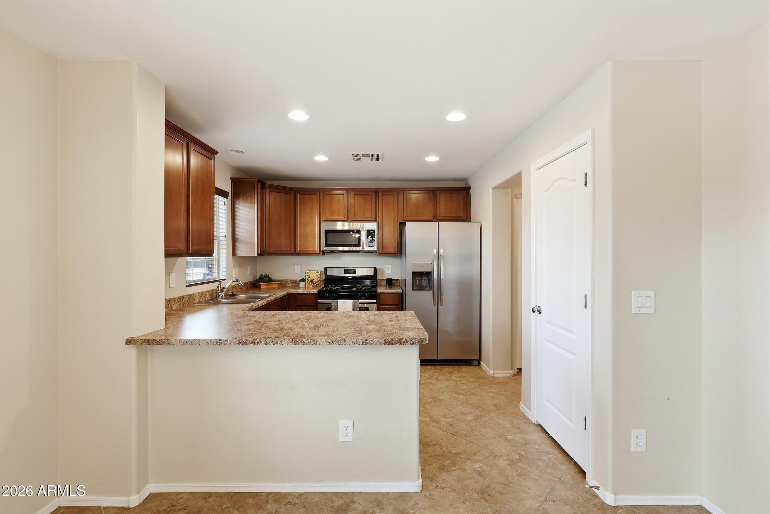 1853 South Balboa Drive Gilbert, AZ 85295 - Photo 14 of 32 a kitchen with stainless steel appliances granite countertop a refrigerator a sink a stove and a refrigerator with wooden floor