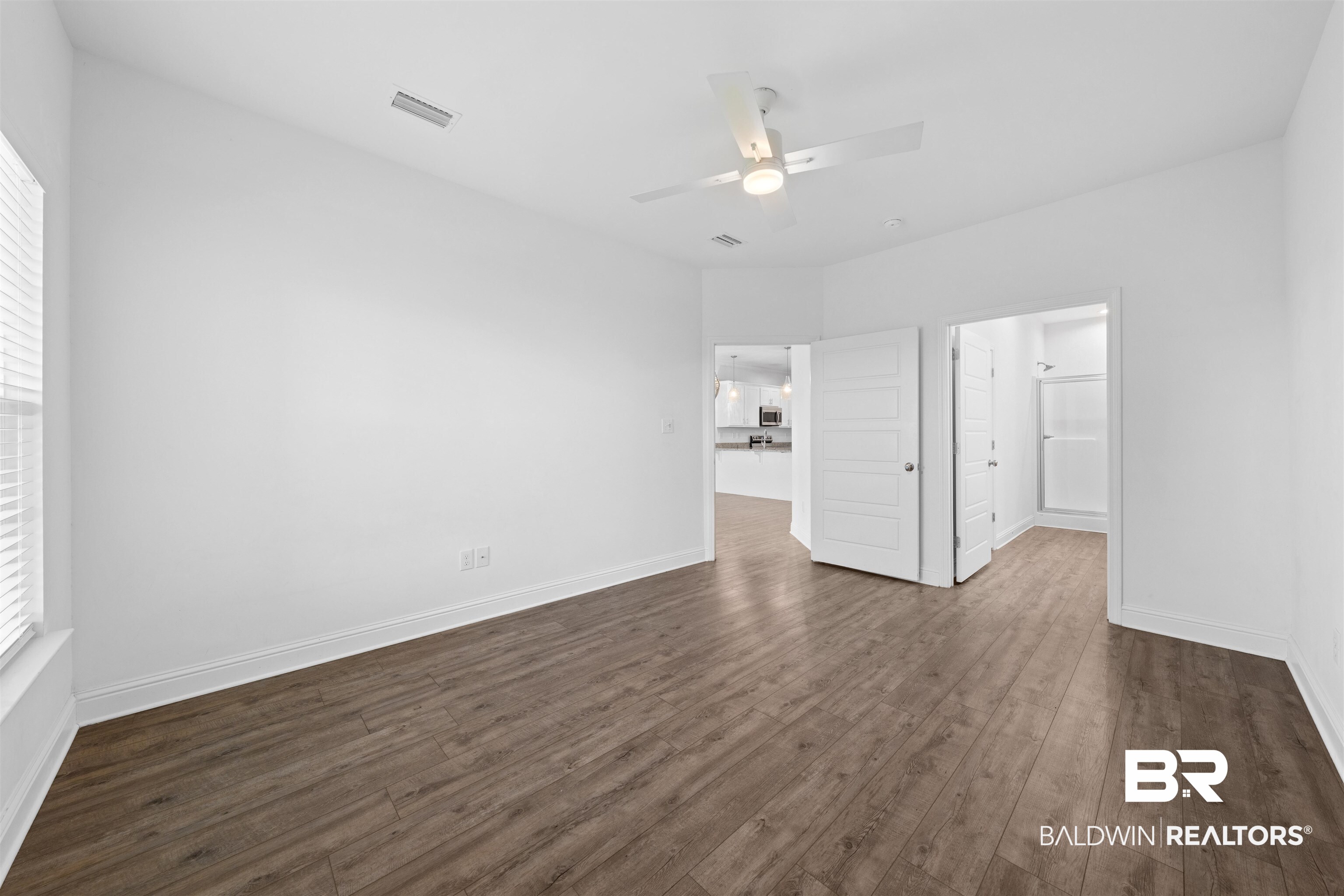 2651 South Juniper Street, Unit 1801 Foley, AL 36535 - Photo 12 of 16 Spacious room featuring wood-finish flooring, white baseboards, and a ceiling fan with integrated lighting