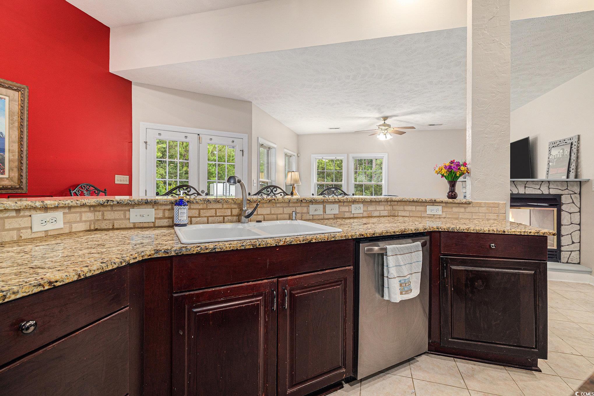 2425 Hunters Trail Myrtle Beach, SC 29588 - Photo 12 of 40 Kitchen with dishwasher, light tile patterned flooring, a stone fireplace, a textured ceiling, and a ceiling fan