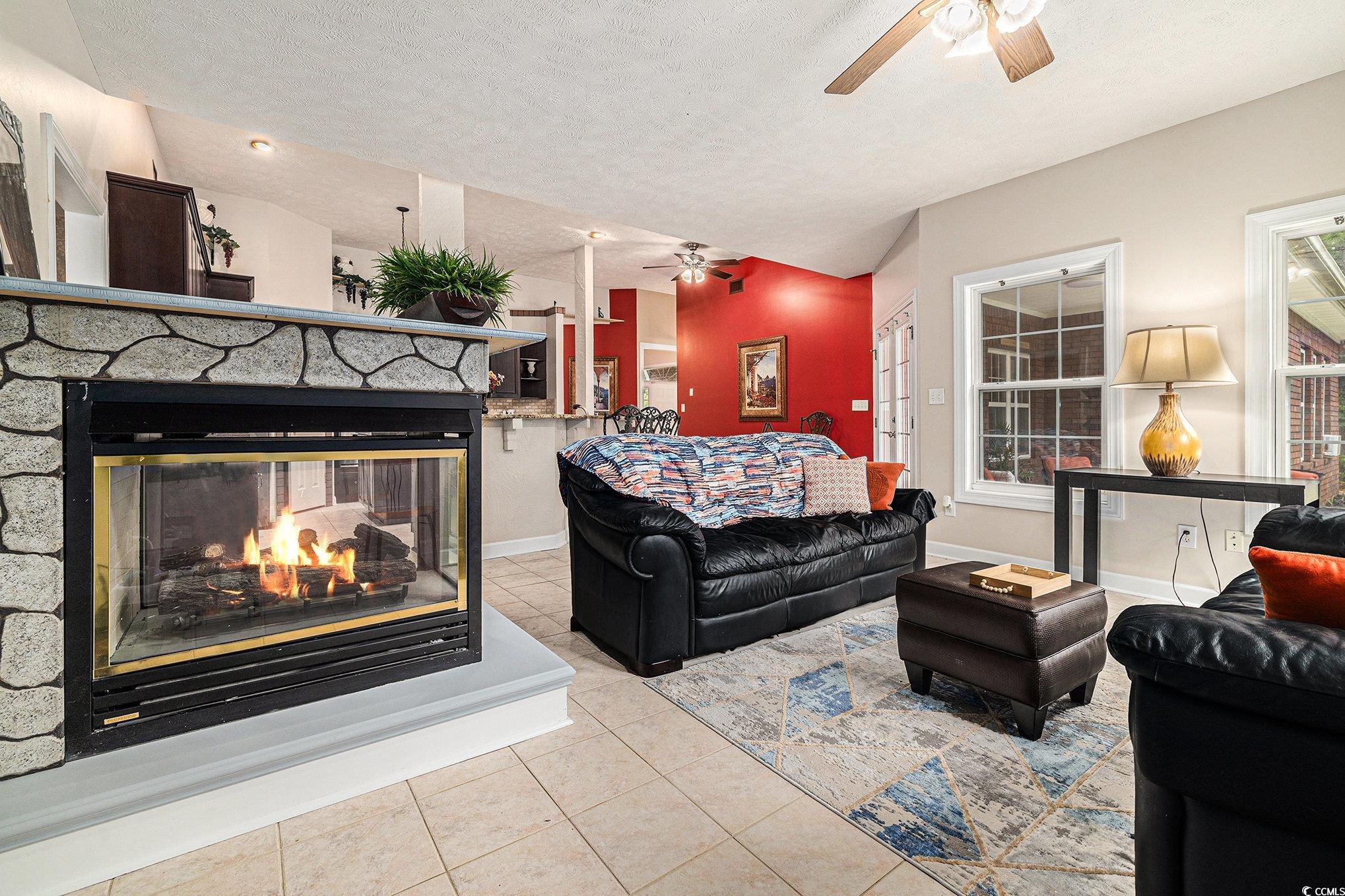 2425 Hunters Trail Myrtle Beach, SC 29588 - Photo 13 of 40 Tiled living area with lofted ceiling, a textured ceiling, a stone fireplace, and a ceiling fan