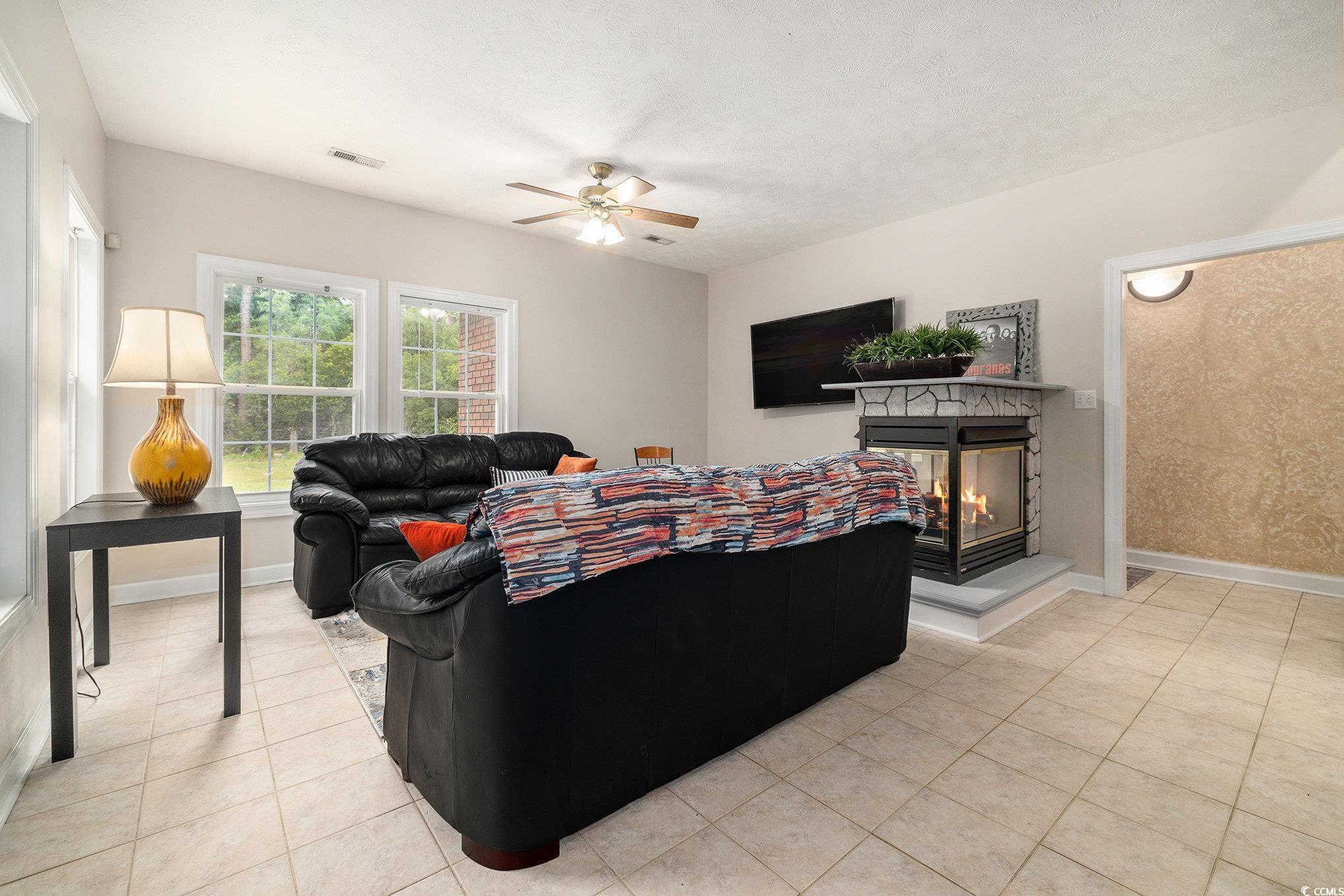 2425 Hunters Trail Myrtle Beach, SC 29588 - Photo 19 of 40 Living room with a multi sided fireplace, light tile patterned floors, and ceiling fan