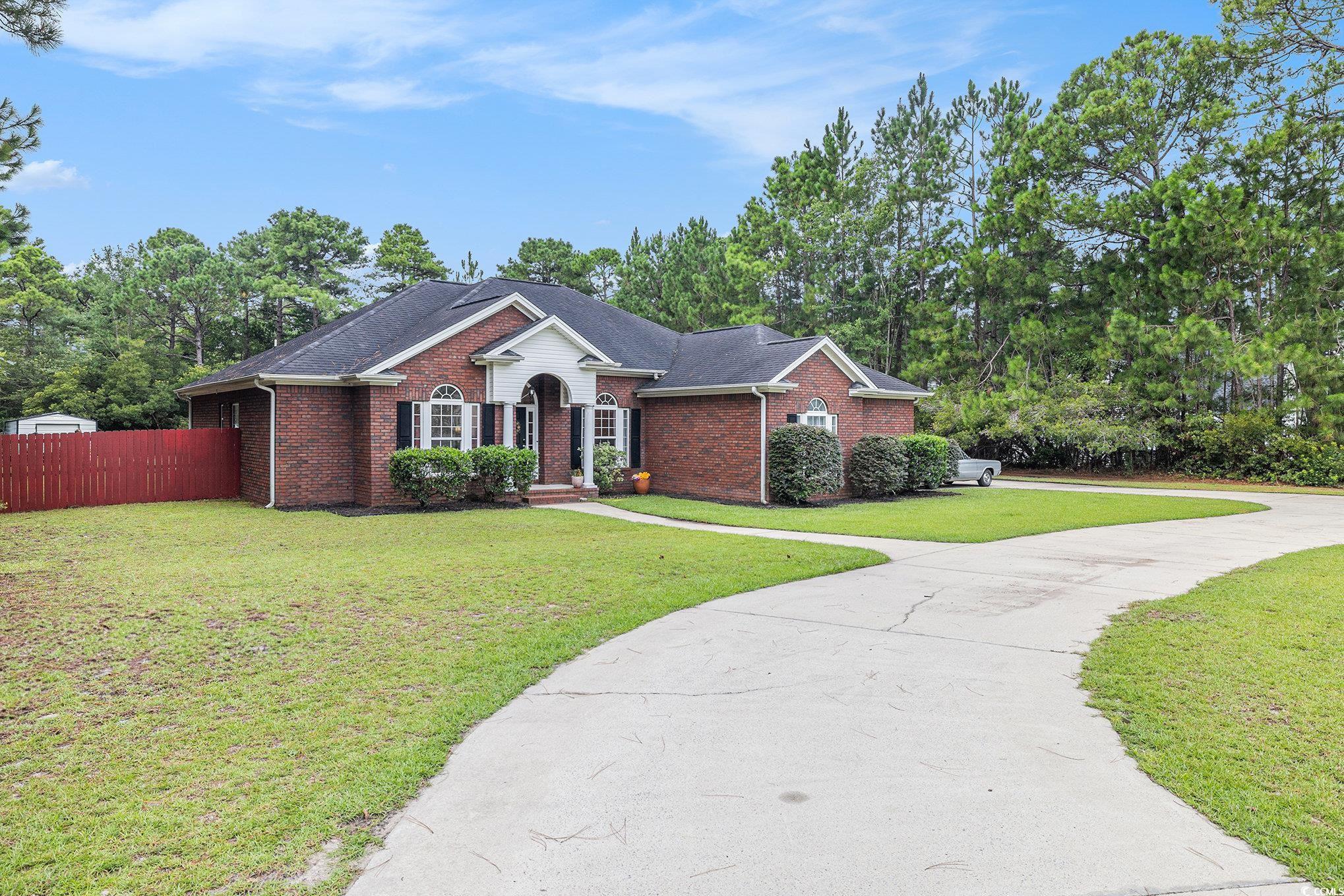 2425 Hunters Trail Myrtle Beach, SC 29588 - Photo 33 of 40 View of front of house featuring brick siding, roof with shingles, concrete driveway, and view of scattered trees