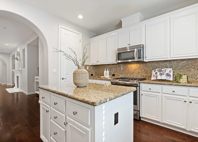 a kitchen with granite countertop a sink stove and cabinets