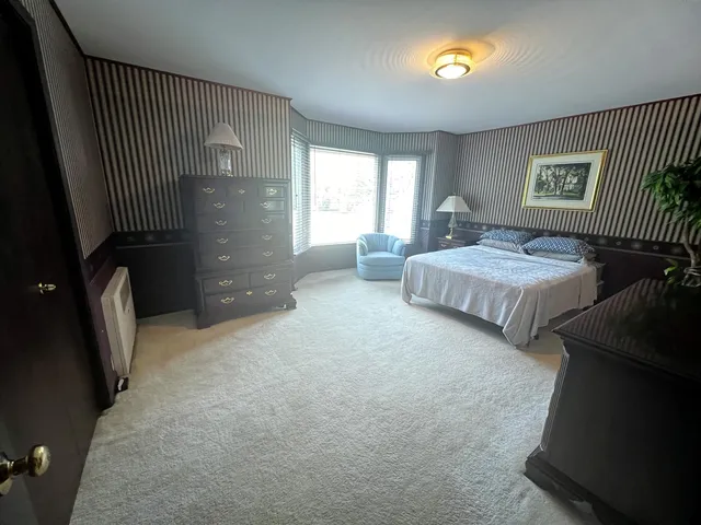 a spacious bedroom with a bed and a lamp with window