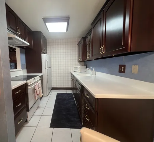 a kitchen with a sink a stove cabinets and a wooden floor