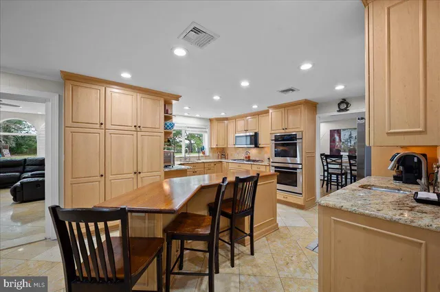 a kitchen with stainless steel appliances granite countertop a refrigerator oven a sink dishwasher and a dining table with chairs