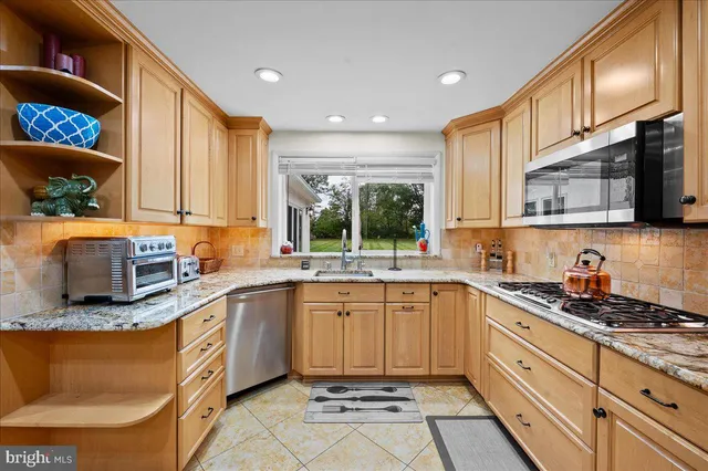 a kitchen with stainless steel appliances granite countertop a sink dishwasher stove and microwave with wooden cabinets