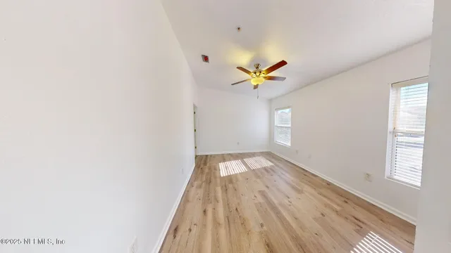 an empty room with wooden floor and chandelier fan
