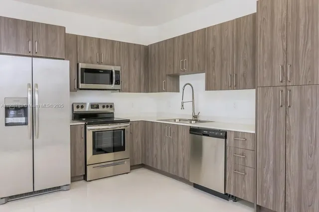 a kitchen with stainless steel appliances a stove microwave and sink