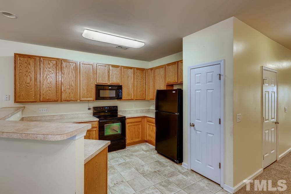 4906 Ravel Stone Court Raleigh, NC 27610 - Photo 7 of 28 a kitchen with granite countertop wooden cabinets a refrigerator stove a sink and dishwasher
