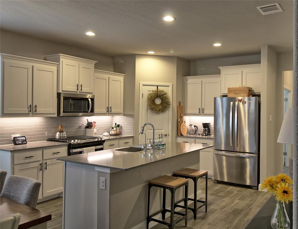 a kitchen with refrigerator a microwave a stove and cabinets