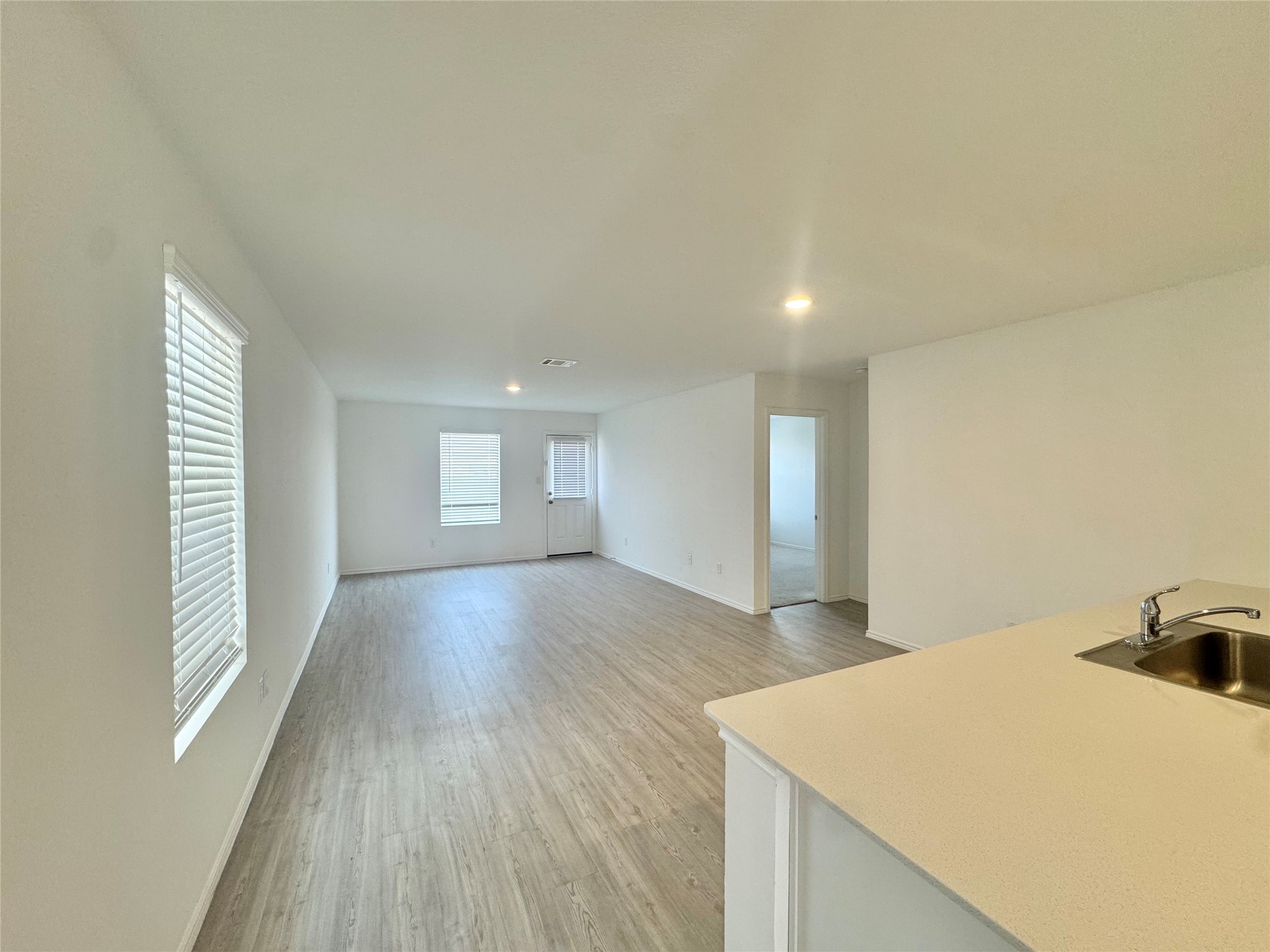 Smooth wood-look flooring and recessed lighting define this versatile open concept living space.