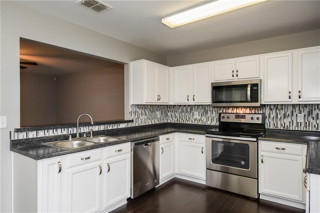926 Walnut Street Burleson, TX 76028 - Photo 11 of 17 Kitchen featuring stainless steel appliances, white cabinets, and dark wood finished floors