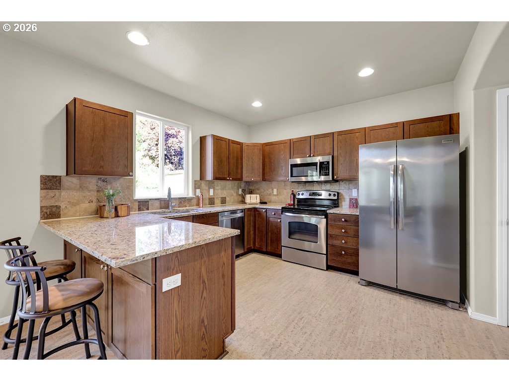 654 North Garden Way Eugene, OR 97401 - Photo 12 of 47 a kitchen with a refrigerator a sink a stove a microwave with a dining table and chairs
