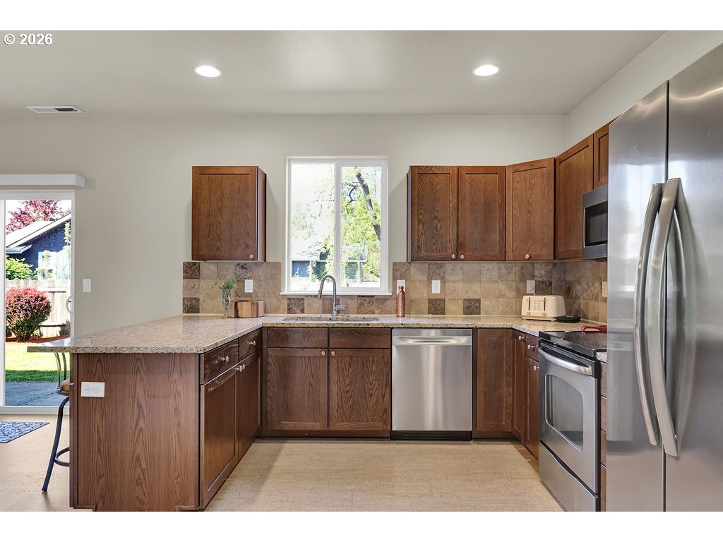 654 North Garden Way Eugene, OR 97401 - Photo 13 of 47 a kitchen with stainless steel appliances granite countertop a sink a stove a refrigerator and cabinets