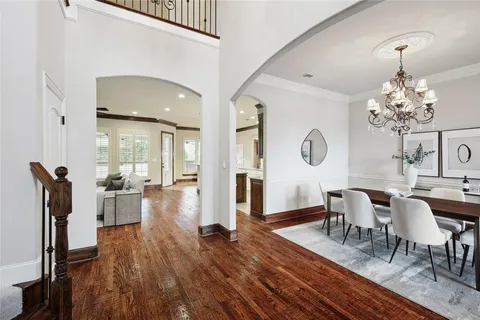 a dining room with wooden floor a chandelier a wooden table and chairs