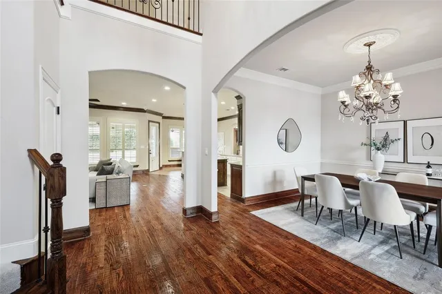 a dining room with wooden floor a chandelier a wooden table and chairs