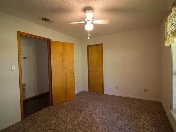 an empty room with a chandelier fan and windows