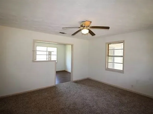 an empty room with windows and a ceiling fan