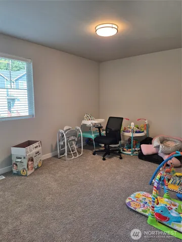 a room with a baby bed a couch and a window