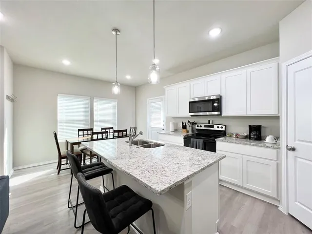 a kitchen with granite countertop white cabinets and black appliances