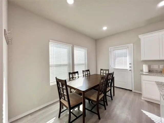 a kitchen with stainless steel appliances kitchen island granite countertop a dining table chairs and a refrigerator