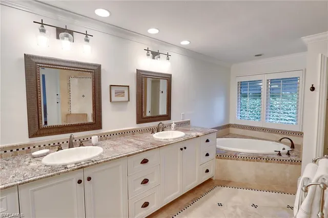 a bathroom with a granite countertop double vanity sink a mirror and a bathtub