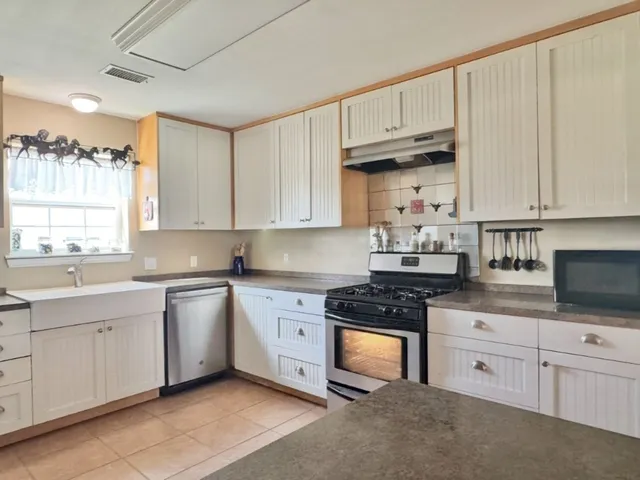 a kitchen with granite countertop a sink cabinets and stainless steel appliances
