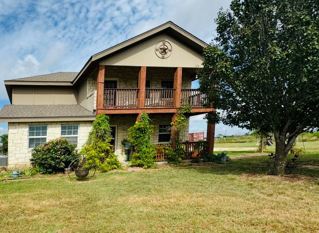 2334 County Road 464 Elgin, TX 78621 - Photo 29 of 39 View of front of property with a balcony, a front lawn, stone siding, and roof with shingles