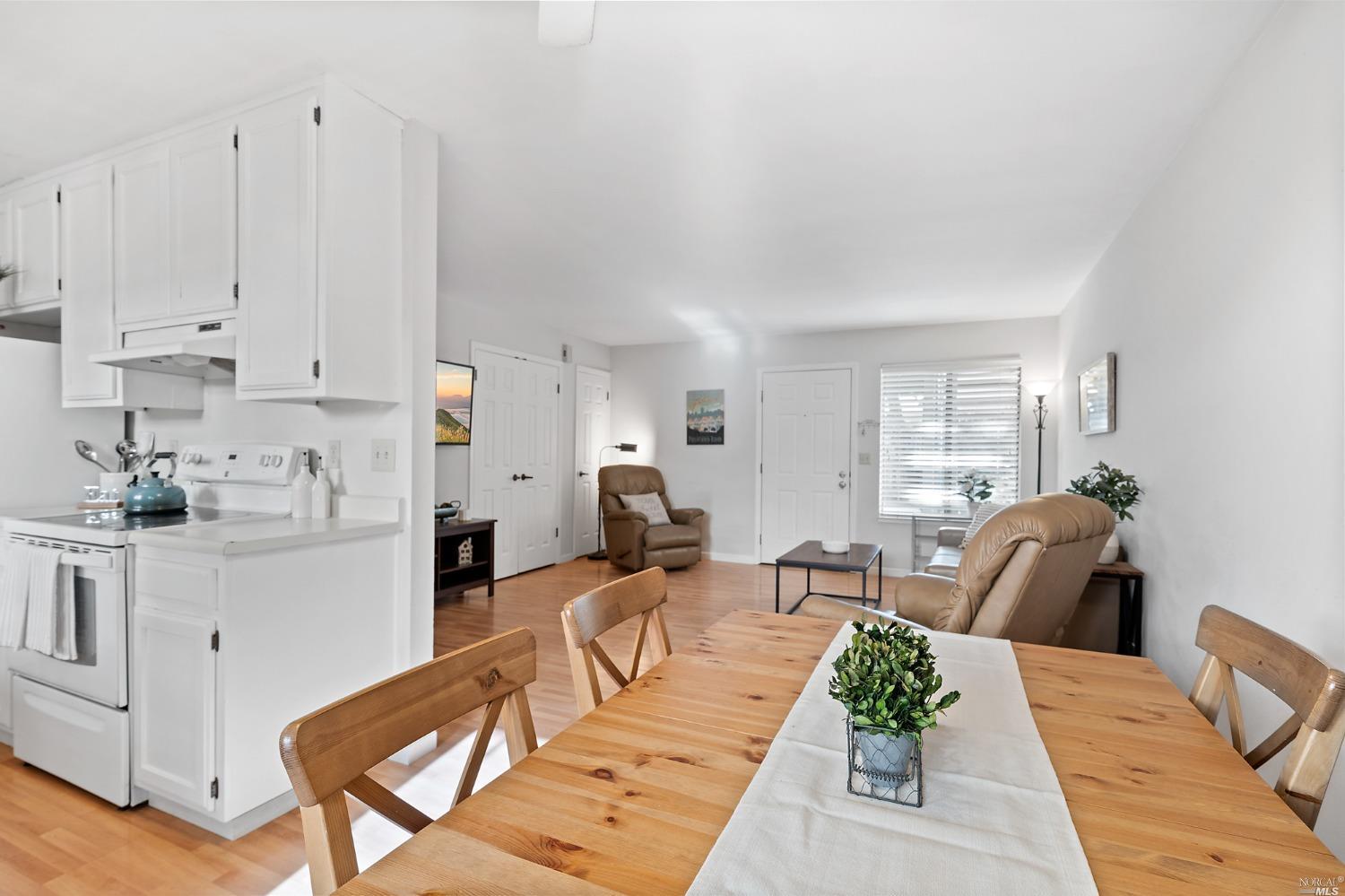 a living room with furniture a rug kitchen view and a window