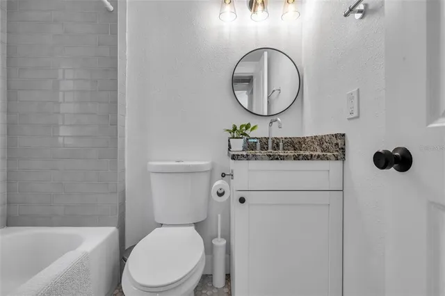 a bathroom with a toilet sink vanity tub and mirror