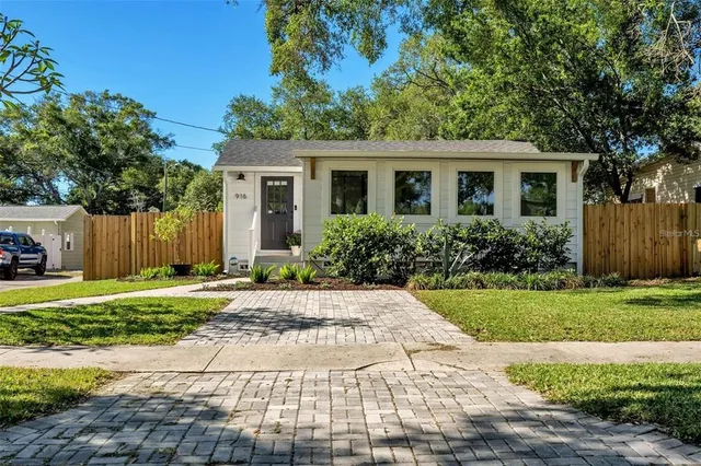 a front view of a house with a yard and potted plants