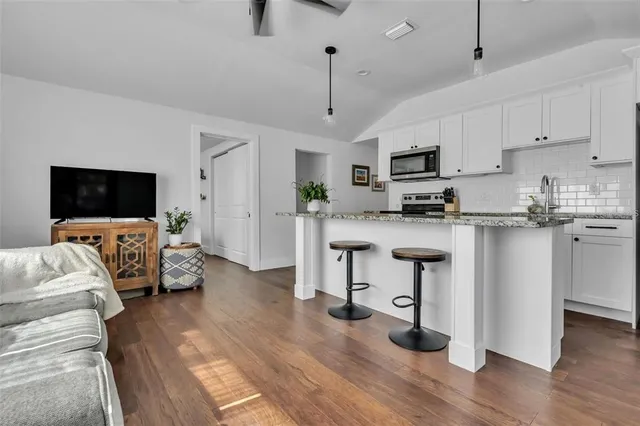 a kitchen with stainless steel appliances granite countertop a stove top oven a sink dishwasher a dining table and chairs with wooden floor