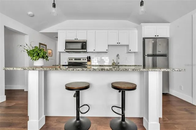 a kitchen with stainless steel appliances granite countertop a refrigerator and a stove top oven