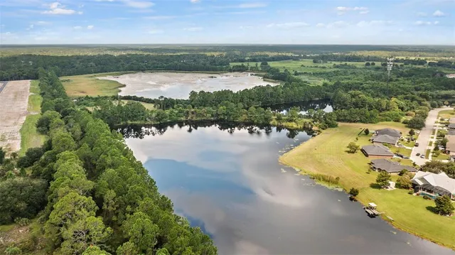 an aerial view of lake residential house with outdoor space and trees in the background