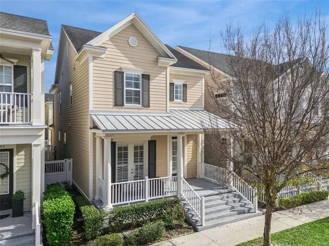 a view of a white house next to a yard with big trees