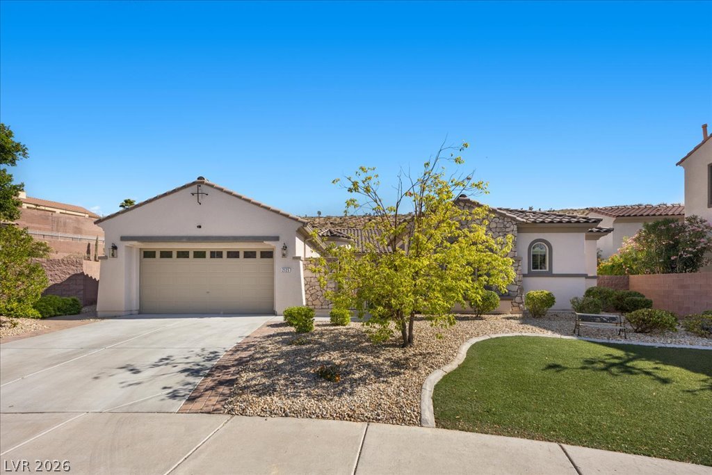 2125 De Rouge Avenue Henderson, NV 89044 - Photo 27 of 96 A well-maintained stucco and stone facade with a terracotta roof, framed by xeriscaping and a neatly trimmed lawn.