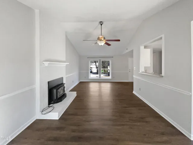 a view of a livingroom with wooden floor a fireplace and windows