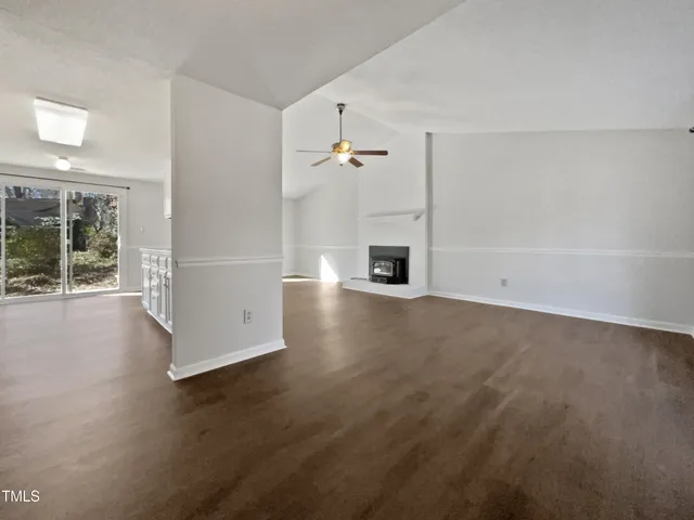 an empty room with wooden floor fireplace and windows