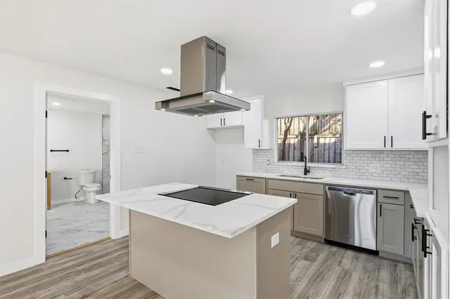 a kitchen with a stove a sink and wooden floor