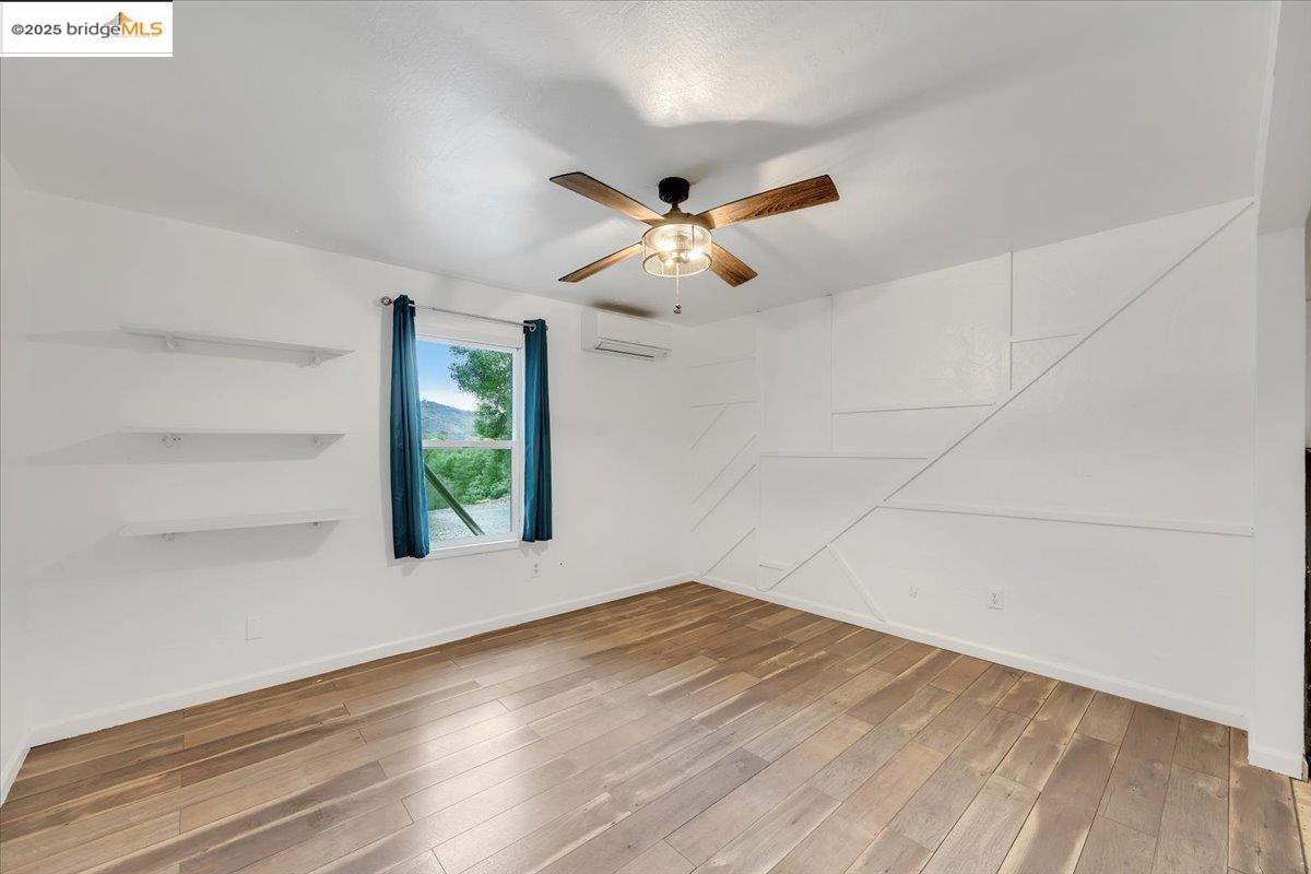 21980 Montgomery Road Sonora, CA 95370 - Photo 15 of 52 Unfurnished room featuring light wood finished floors, a ceiling fan, and a wall mounted air conditioner