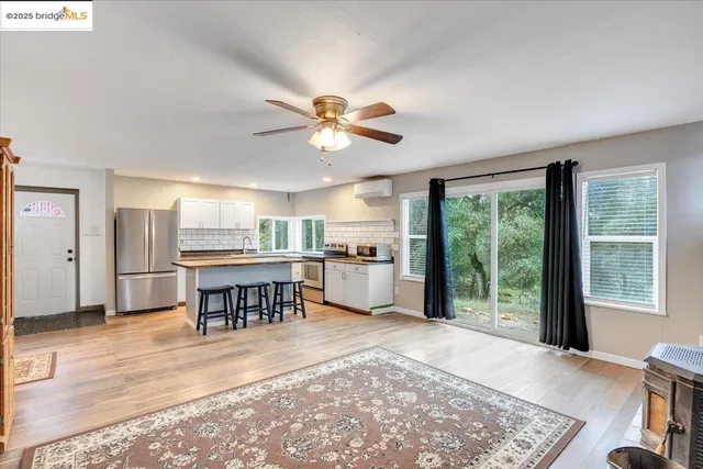 a open kitchen with stainless steel appliances granite countertop a stove dining table chairs and a large window