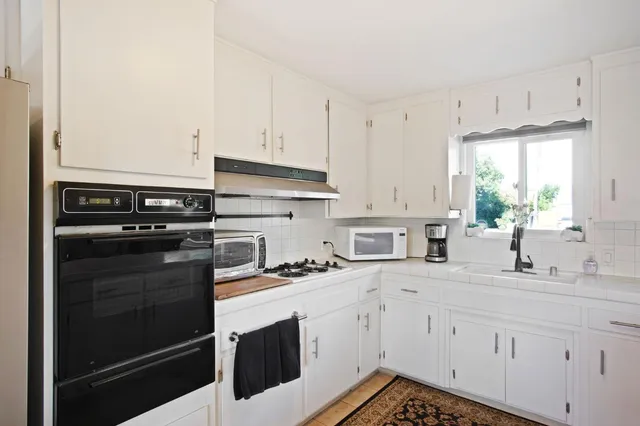 a kitchen with granite countertop white cabinets and white appliances