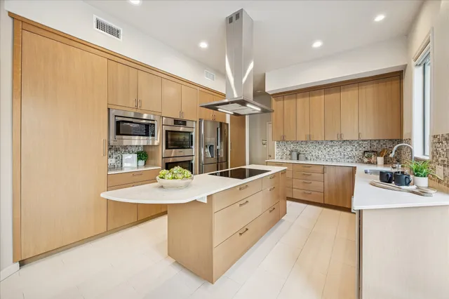 a large kitchen with a large counter top a sink stainless steel appliances and cabinets